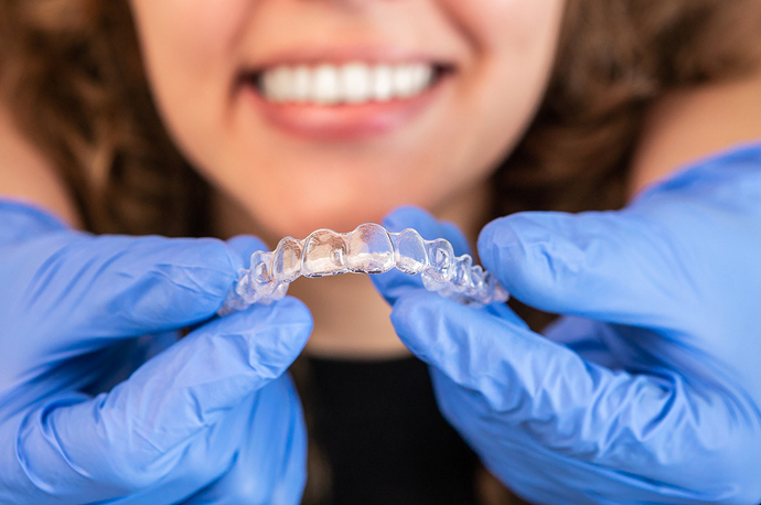 Close-up of an orthodontist holding an Invisalign® aligner in front of a patient