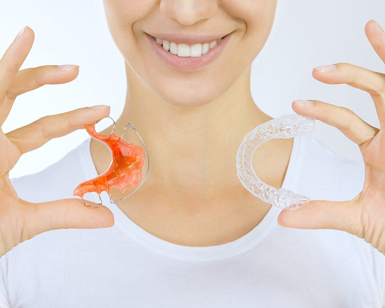 close up of smiling woman holding two retainers