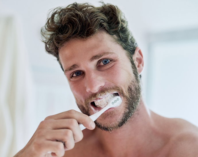 Close up of a man brushing his teeth and getting toothpaste all over his mouth