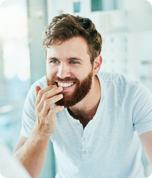 Man smiling and examining his smile in the mirror
