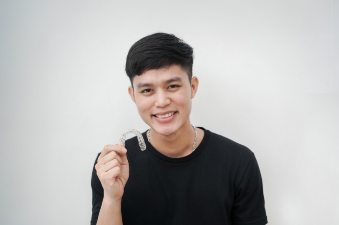 Handsome teen holding his Invisalign aligner in front of him