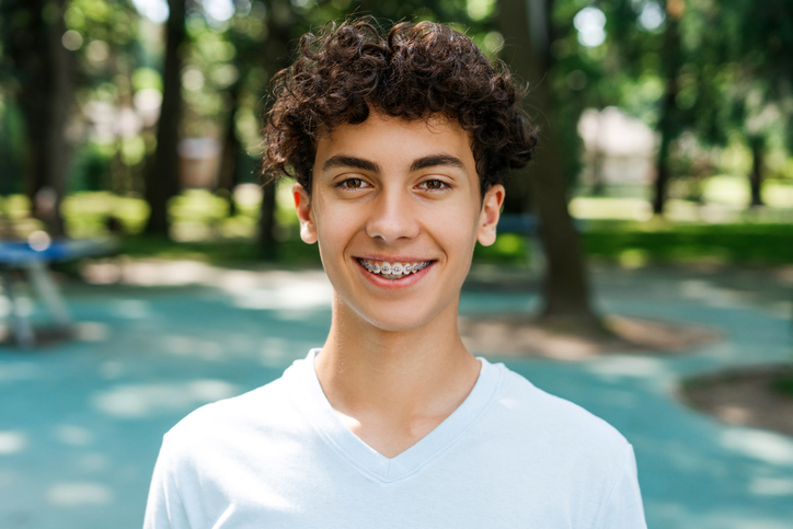 Young man with braces smiling in the park on a spring afternoon