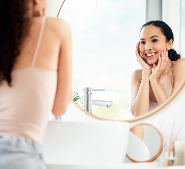 smiling woman looking in mirror holding her hands to face