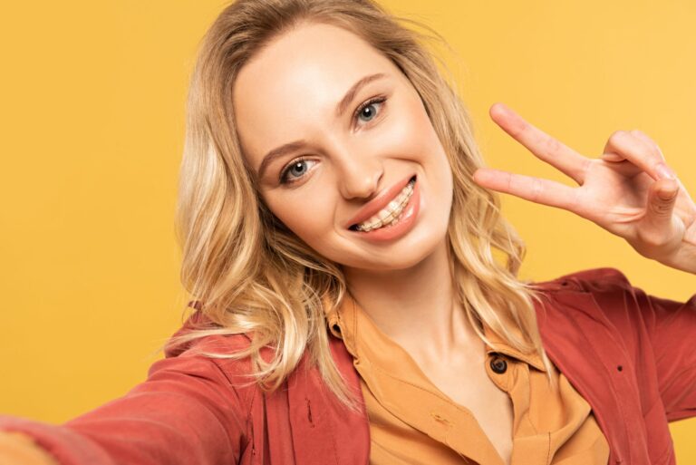 Smiling teen with braces making the peace sign with her fingers