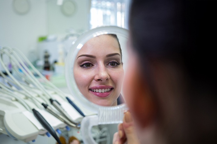 Woman looking at her smile in the mirror at her orthodontics appointment
