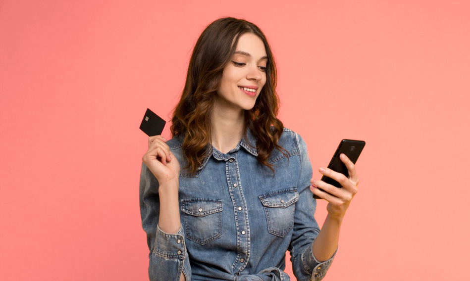 A Woman Holding A Credit Card While Looking At Her Phone