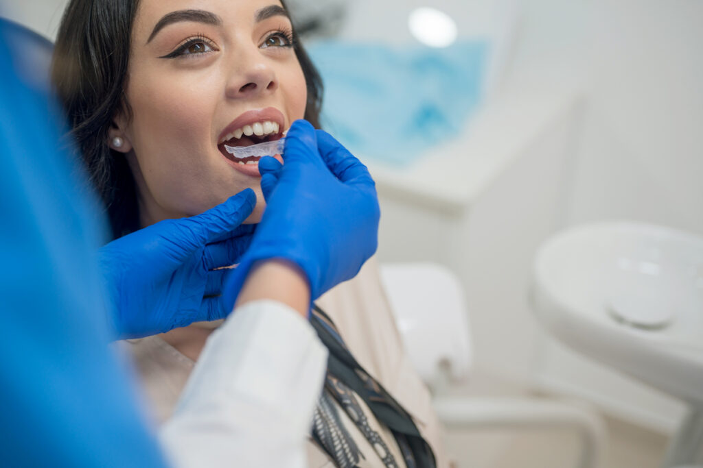 Photogenic woman having an Invisalign aligner placed onto her bit by her orthodontist