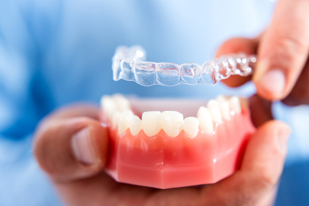 Orthodontist applying an Invisalign® aligner to a dental model in front of a patient