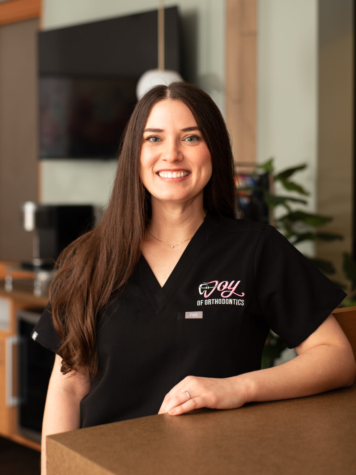 Portrait Of Dr Joy Gerasco inside the practice wearing black scrubs.