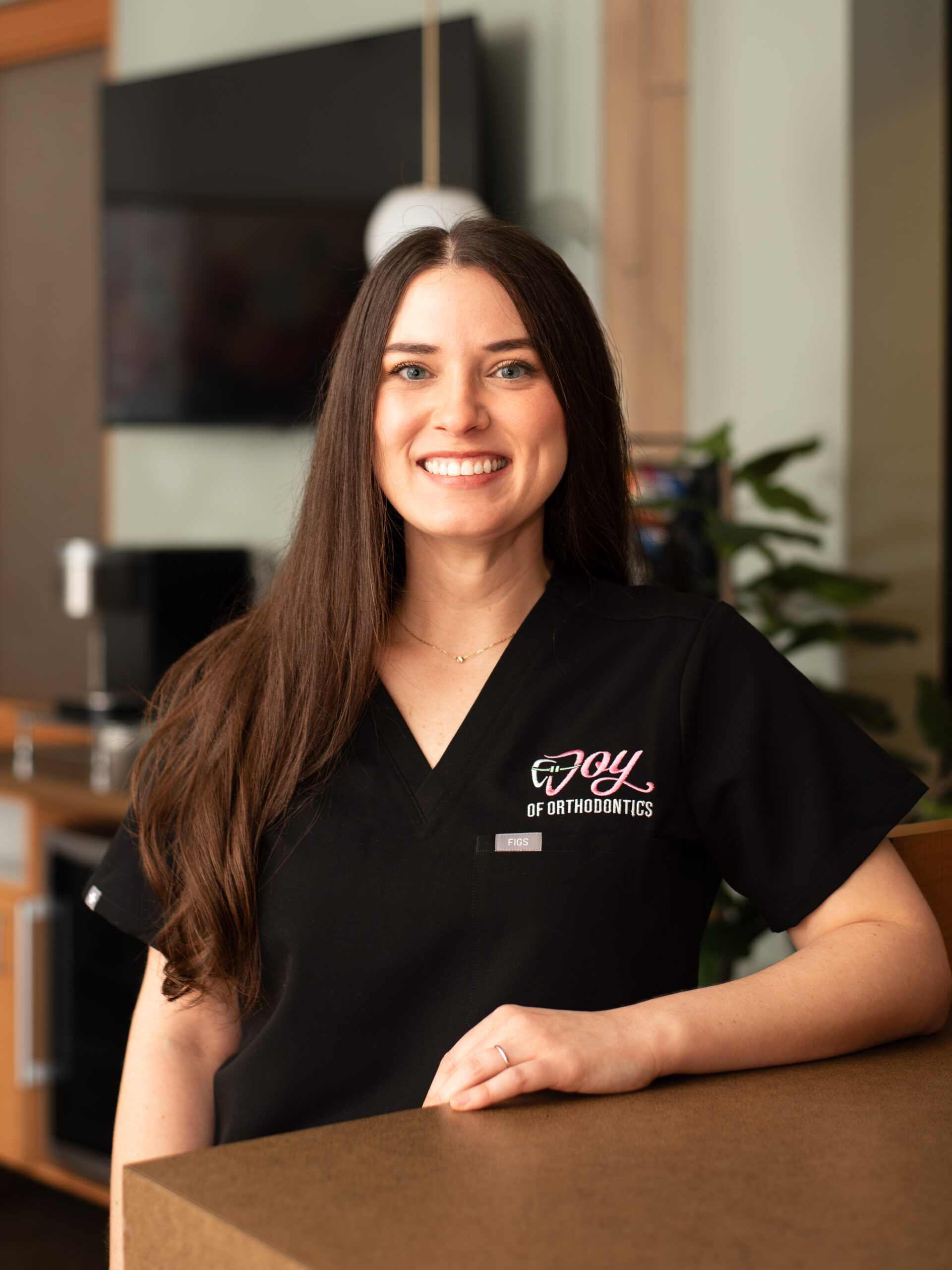 Portrait Of Dr Joy Gerasco inside the practice wearing black scrubs.